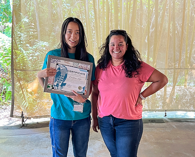 two people stand together while one holds an award