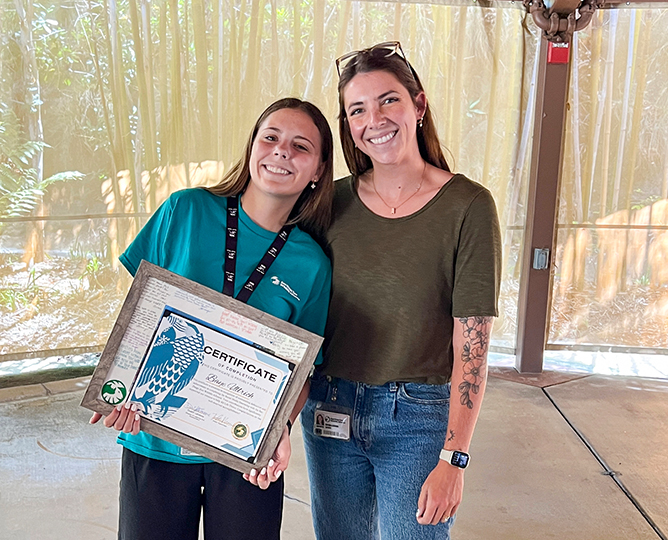 two people stand together while one holds an award